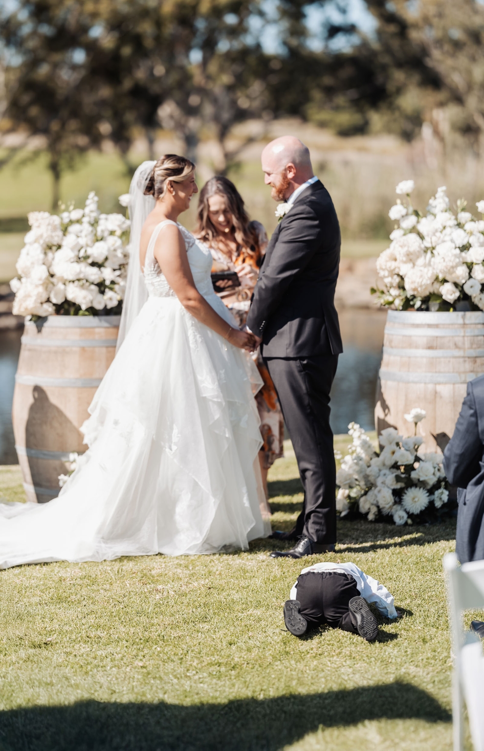 lloyd brothers wedding - dajana & tom 13 Outdoor wedding ceremony with couple exchanging vows, child playing, and scenic landscape backdrop.