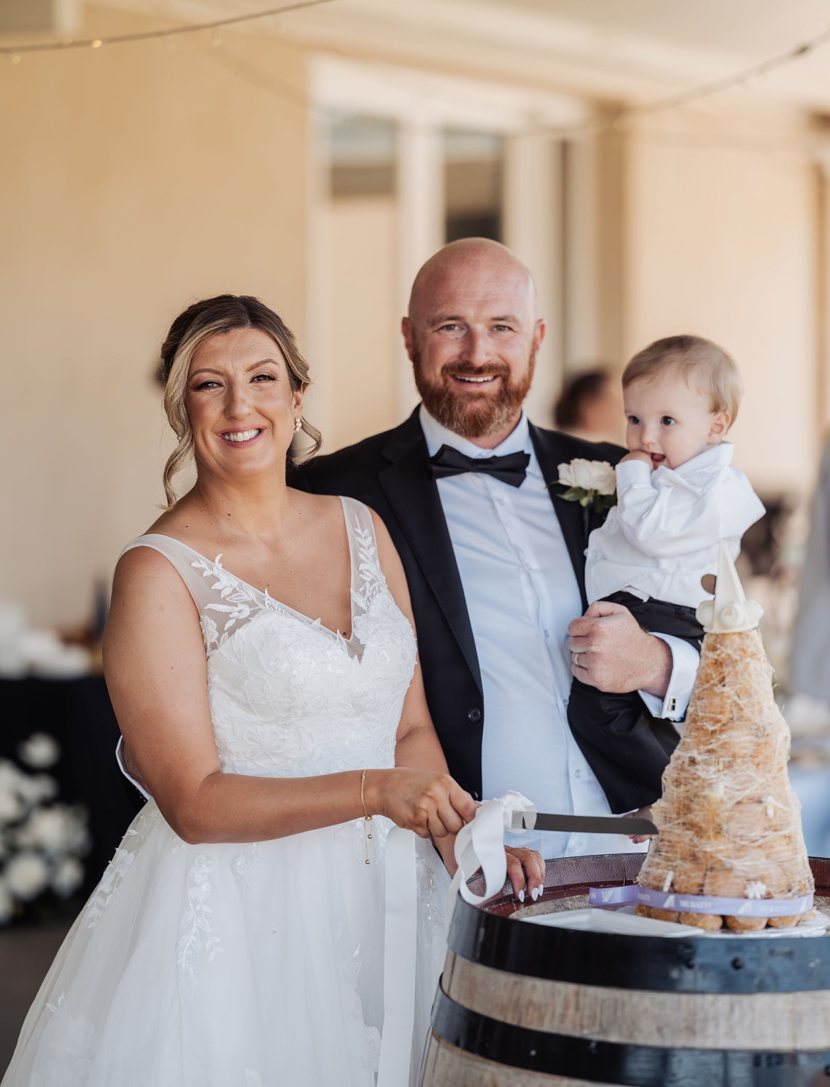 lloyd brothers wedding - dajana & tom 41 Bride and groom cut croquembouche with child at wedding celebration.