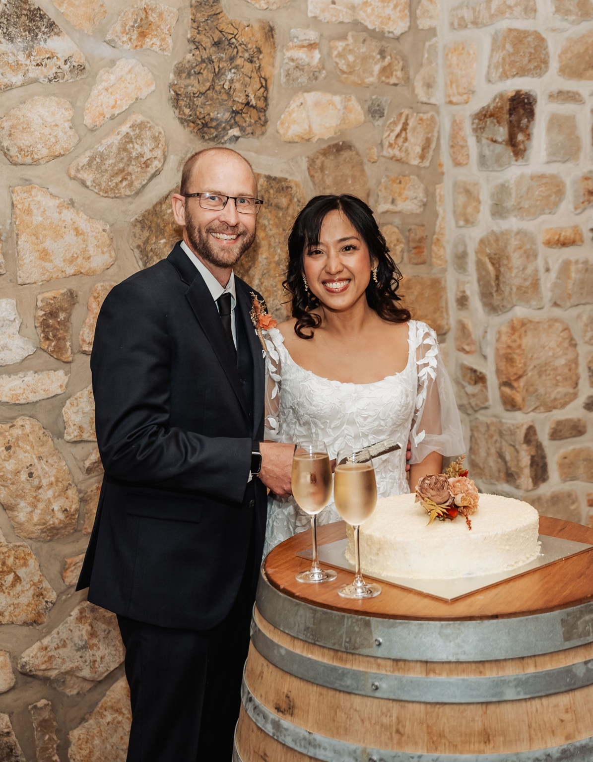 adelaide hills wedding at the manor - jo & dan 61 Wedding couple toasts with champagne beside rustic cake at stone wall reception.