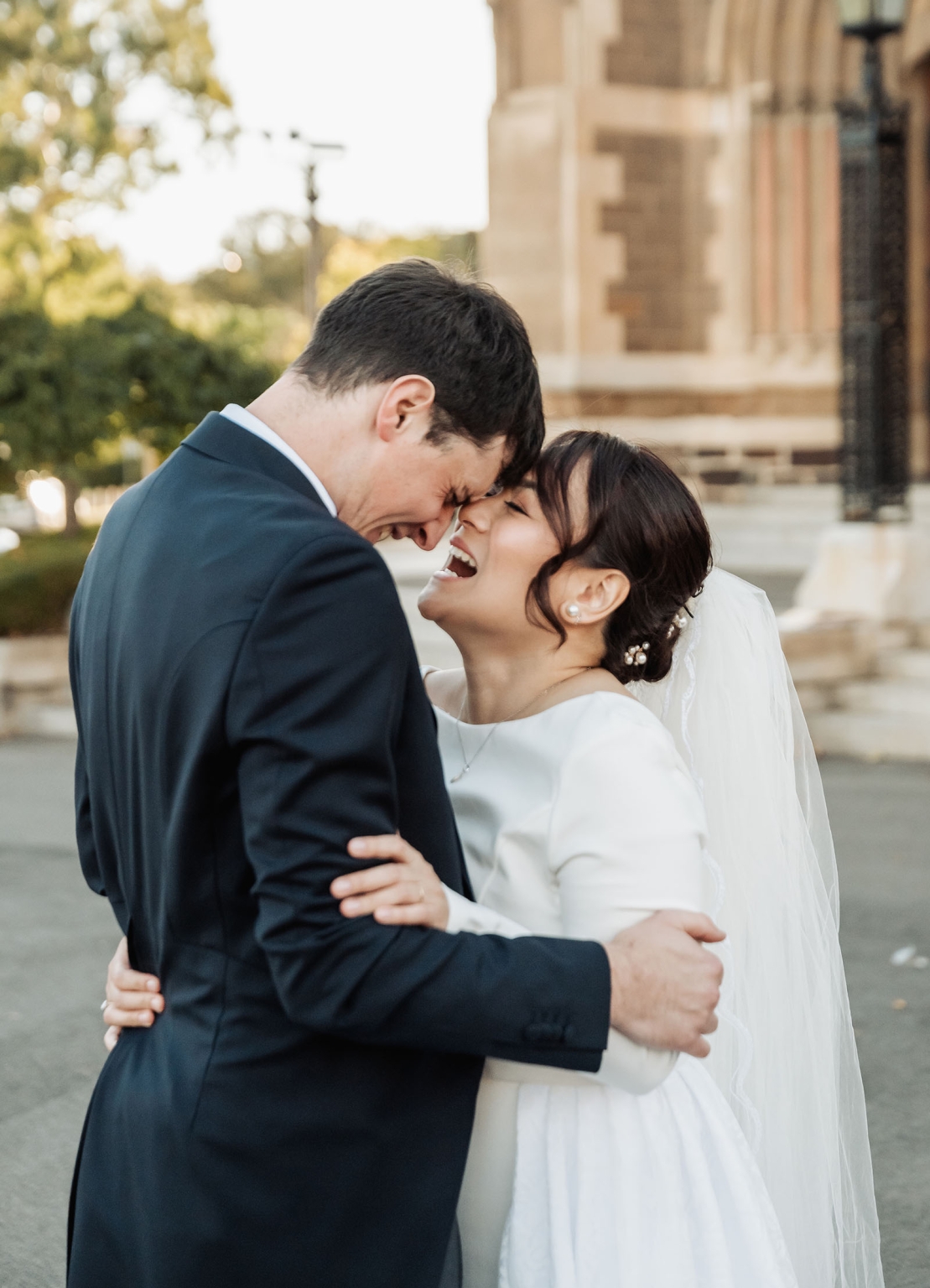 adelaide's st peter's cathedral wedding - irish & nick 35 Joyful bride and groom embracing during romantic outdoor wedding ceremony.