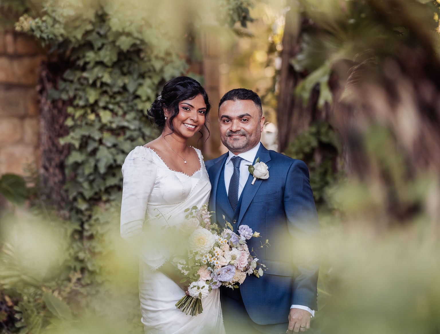 manor wedding in basket range - methmini & aravinda 145 Joyful couple on wedding day in lush garden, elegant attire and vibrant bouquet.