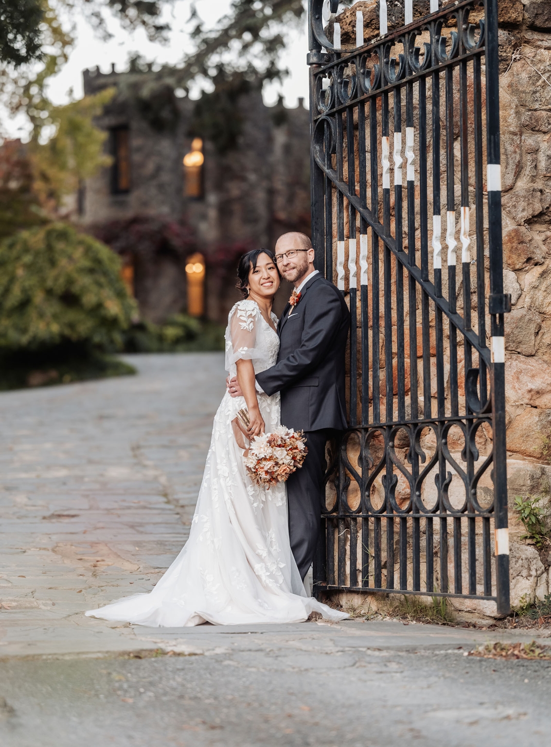 adelaide hills wedding at the manor - jo & dan 48 Newlywed couple posing by ornate iron gate at historic wedding venue.
