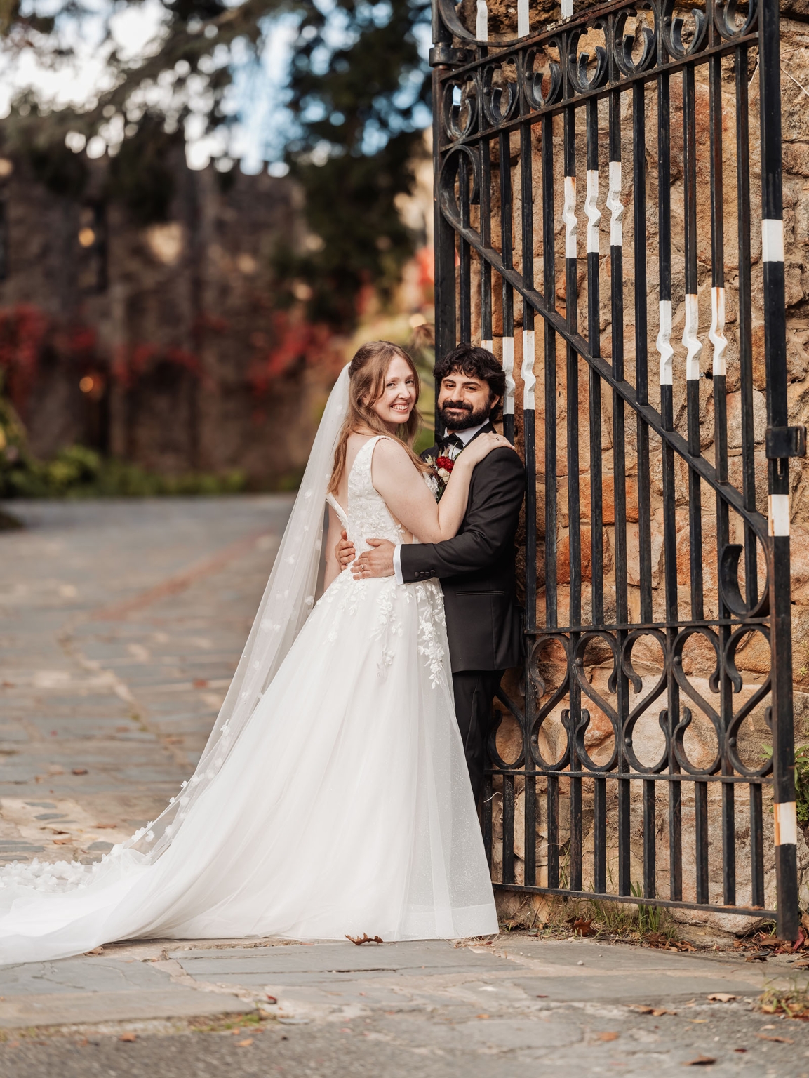 beautiful manor basket range wedding - sophie & theodore 124 Wedding couple by iron gate with autumn foliage, elegant attire, and romantic ambiance.