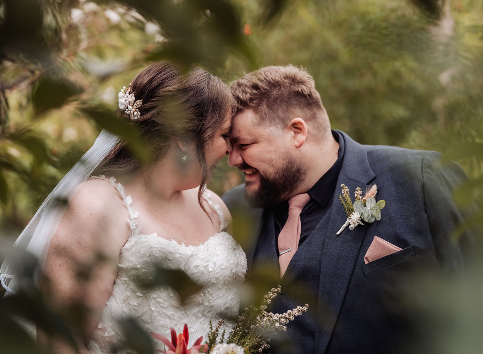 comida wedding - georgia & james 36 Bride and groom share tender moment amidst lush greenery on their wedding day.