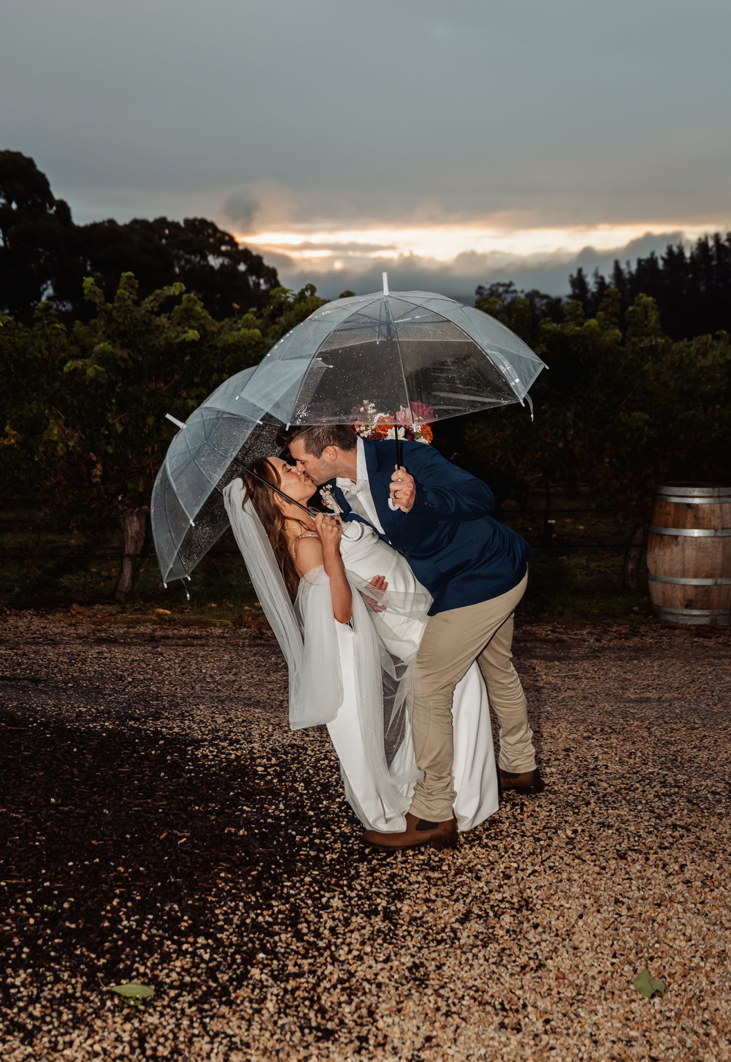 the lane vineyard wedding - caitlyn & craig 125 Romantic newlyweds kiss under umbrellas in vineyard after rain.