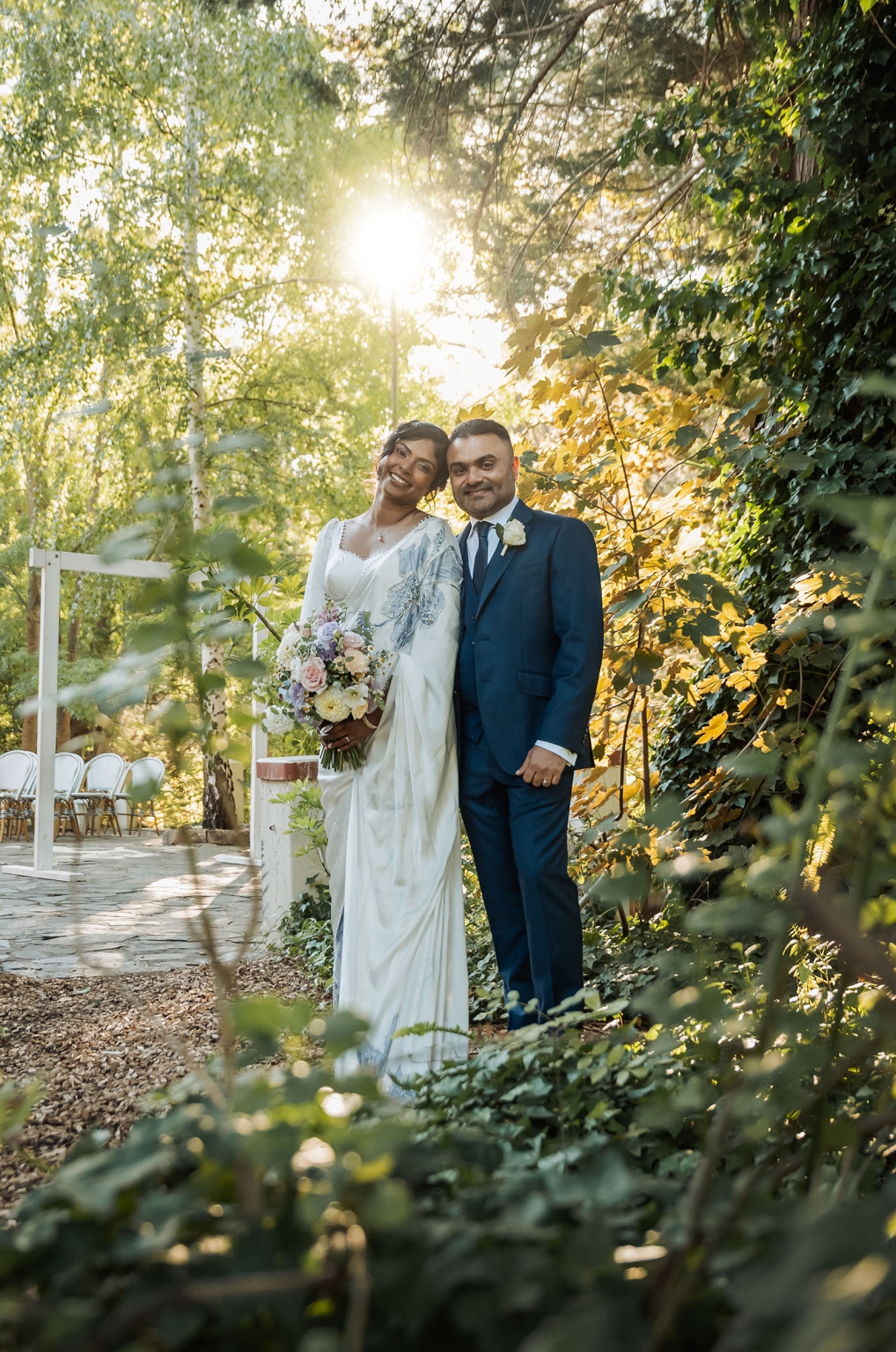 manor wedding in basket range - methmini & aravinda 148 Bride and groom in elegant attire, exchanging love in a sunlit garden wedding.