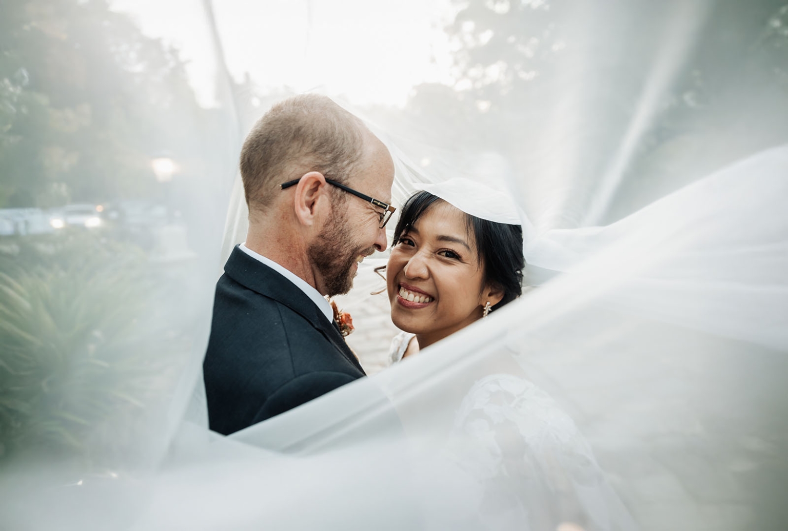 adelaide hills wedding at the manor - jo & dan 44 Joyful bride and groom share romantic wedding portrait beneath flowing veil.