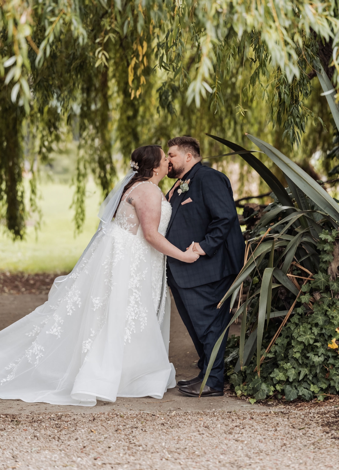comida wedding - georgia & james 20 Bride and groom share a kiss, surrounded by lush greenery on their wedding day.