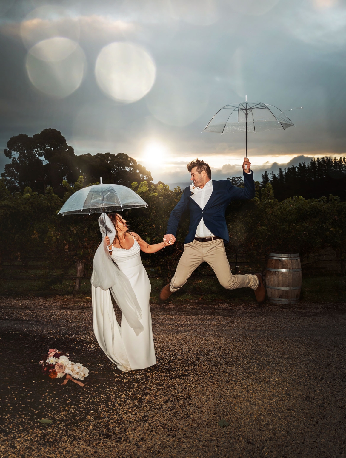 the lane vineyard wedding - caitlyn & craig 126 Joyful newlyweds in vineyard, sharing umbrella, sunlight creating romantic atmosphere.
