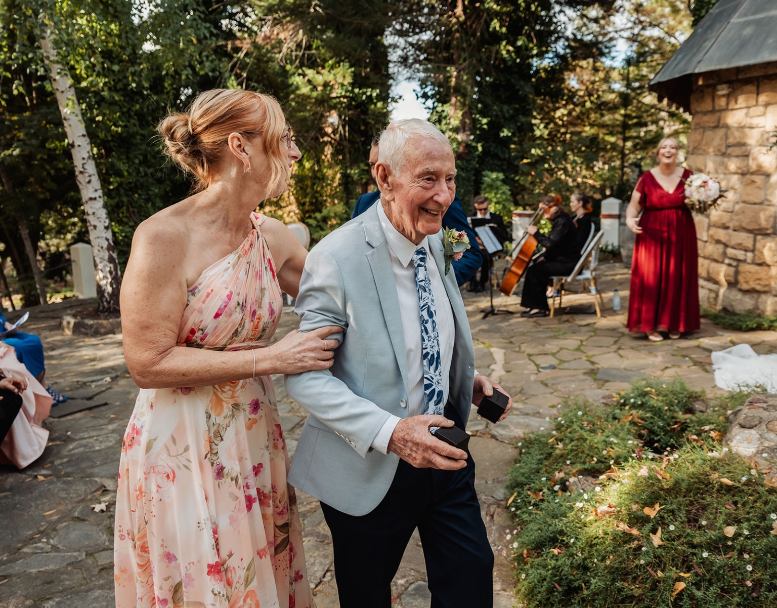 beautiful manor basket range wedding - sophie & theodore 105 Outdoor wedding ceremony with joyful couple, musicians, floral gown, and rustic stone structure.