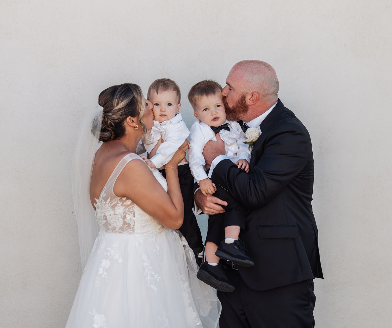 lloyd brothers wedding - dajana & tom 21 Bride and groom lovingly kiss children, celebrating a joyful wedding family moment.