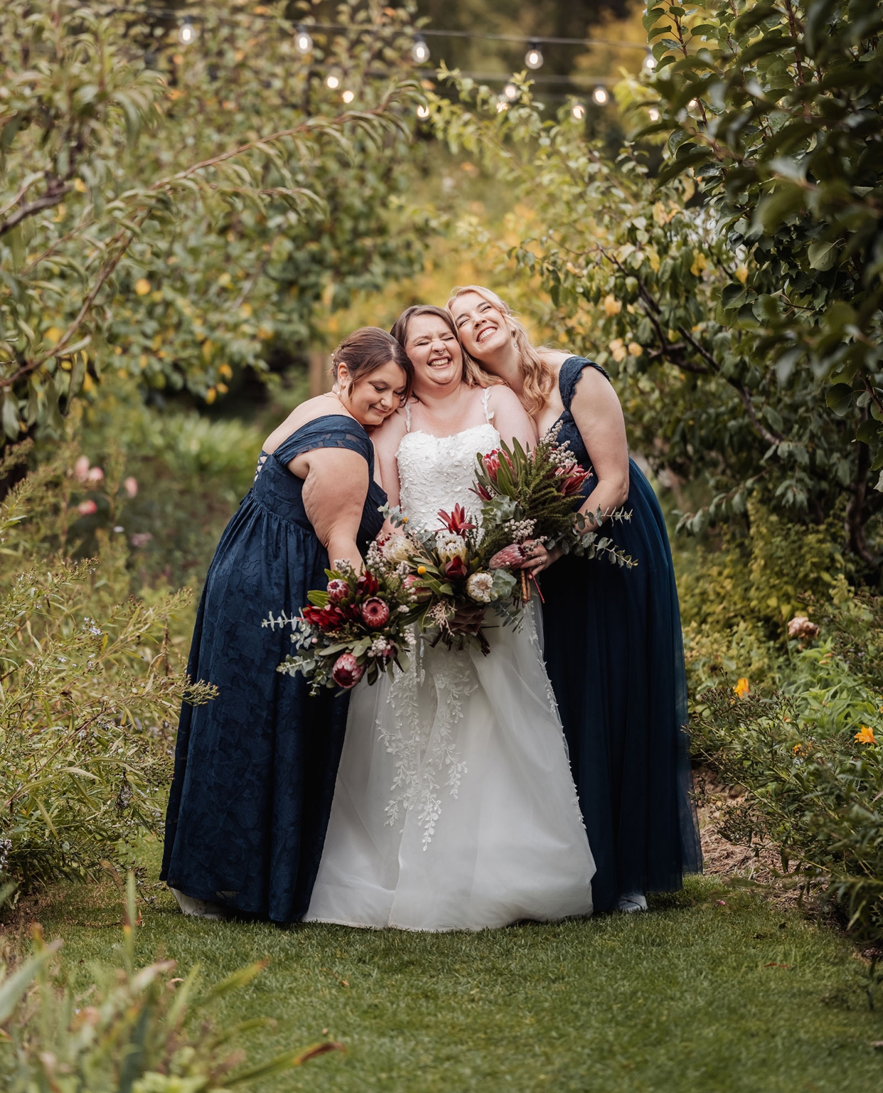 comida wedding - georgia & james 31 Bride and bridesmaids celebrating in a garden with bouquets and navy gowns.