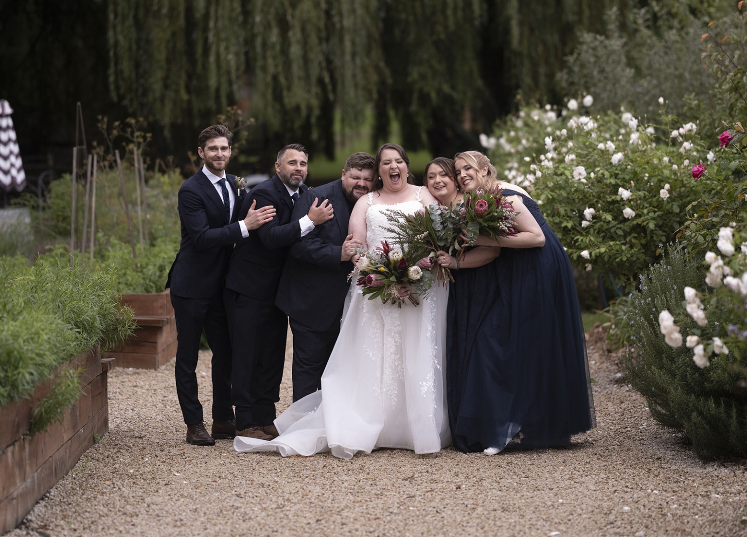 comida wedding - georgia & james 38 Joyful wedding ceremony: bride, groomsmen, bridesmaids amid lush greenery and vibrant flowers.