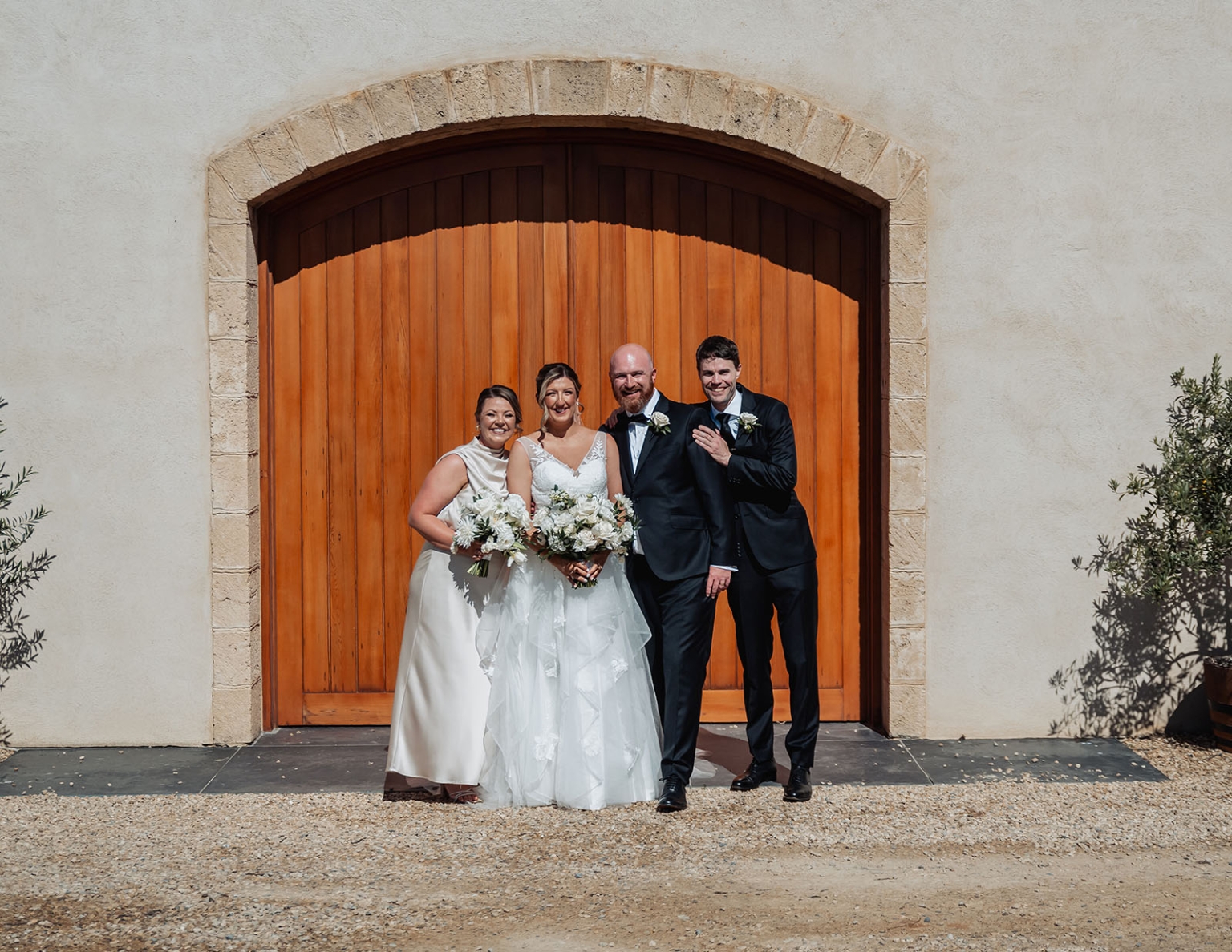 lloyd brothers wedding - dajana & tom 27 Elegant wedding group in front of rustic wooden door, bride and groom joyful.