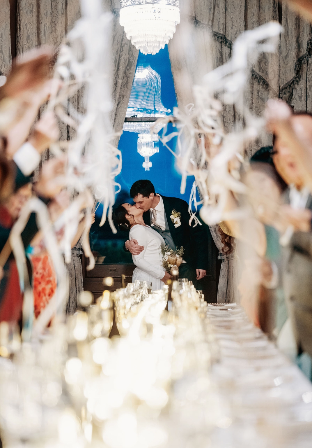 adelaide's st peter's cathedral wedding - irish & nick 55 Bride and groom kiss at elegant wedding reception with streamers and chandelier.