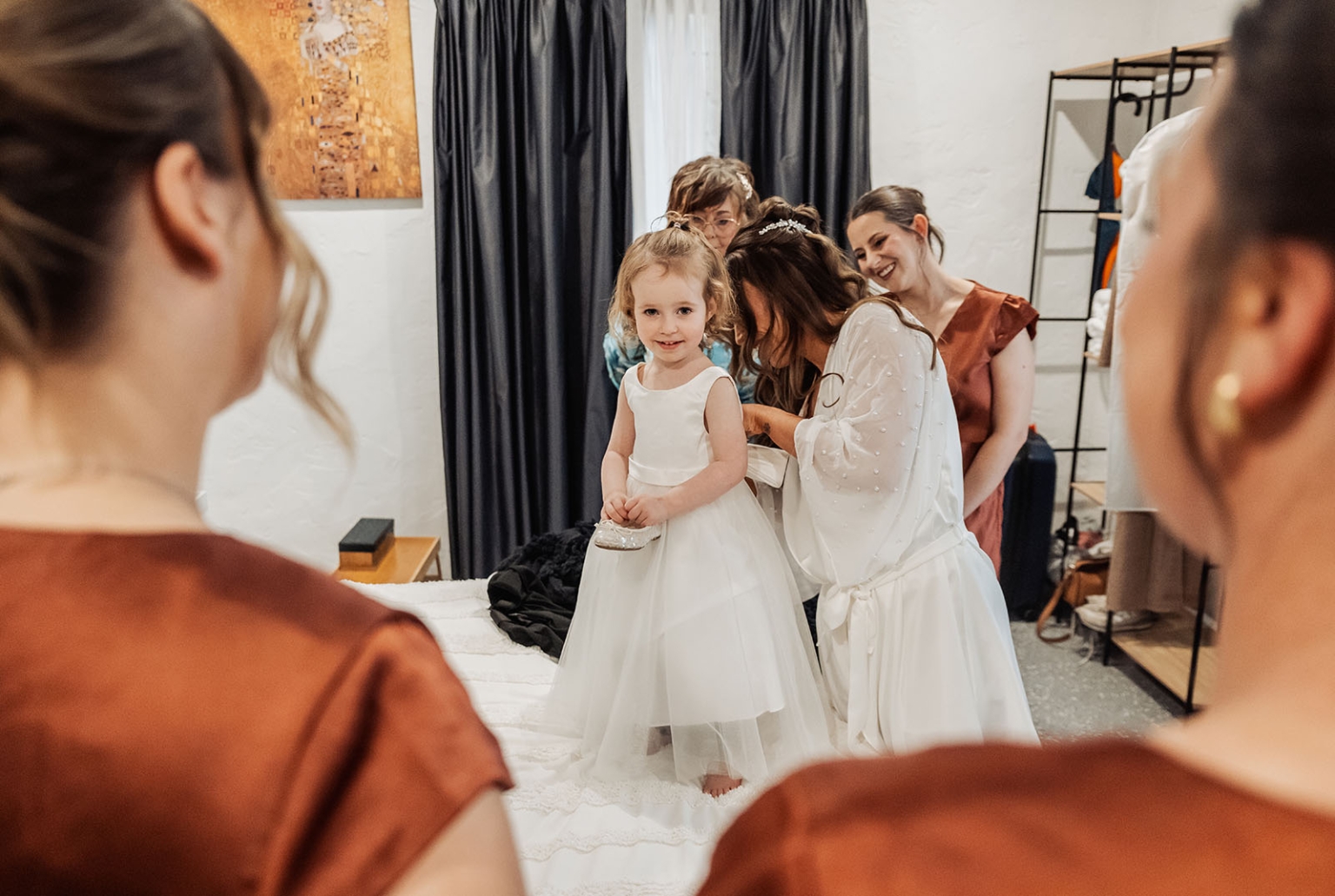 the lane vineyard wedding - caitlyn & craig 86 Young girl in white dress surrounded by bridesmaids during wedding preparation.