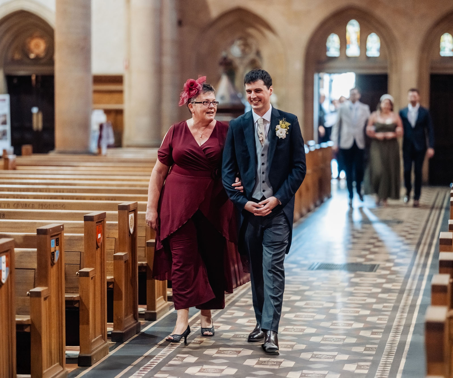adelaide's st peter's cathedral wedding - irish & nick 12 Groom escorts woman down church aisle during joyful wedding procession.