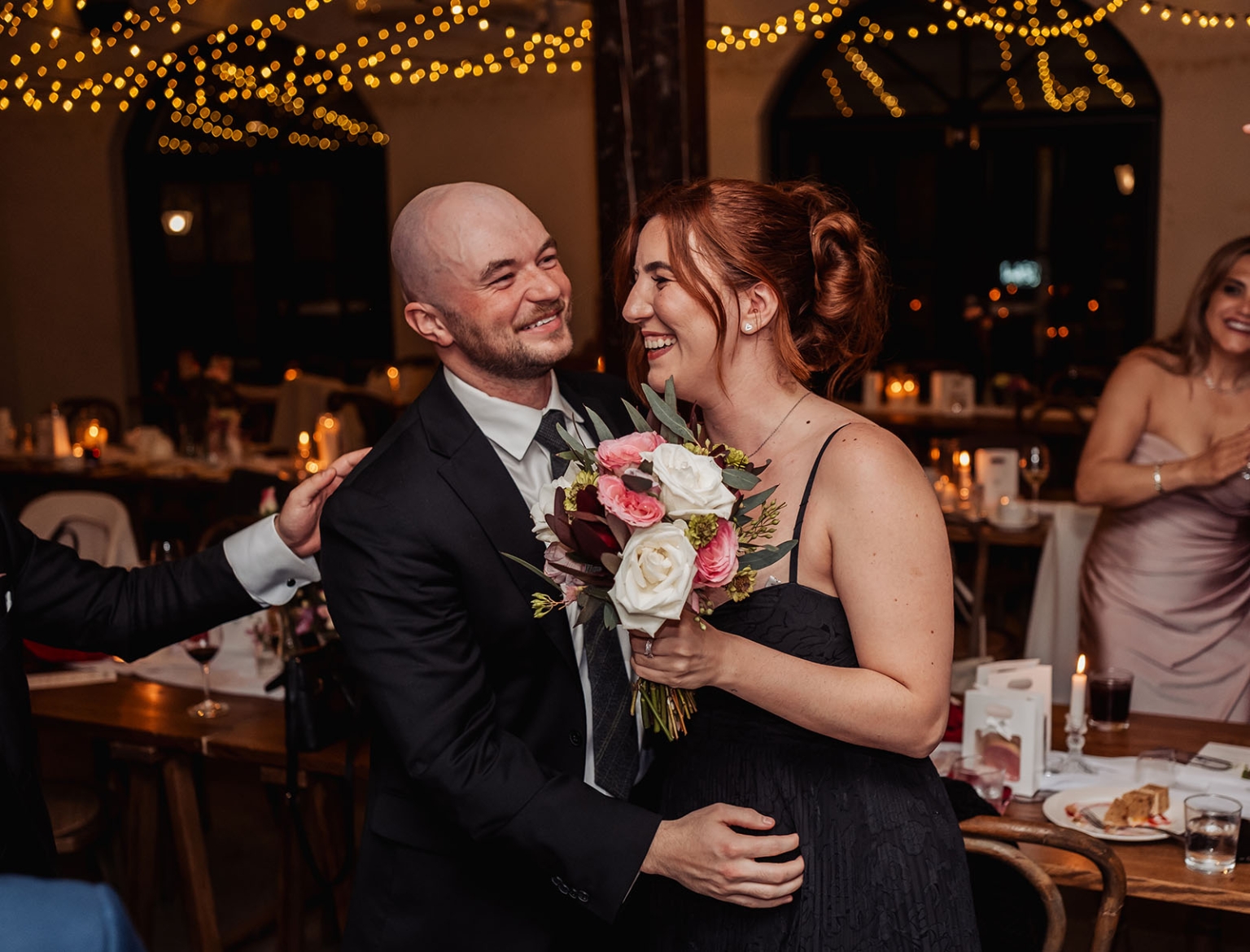beautiful manor basket range wedding - sophie & theodore 151 Joyful wedding reception couple laughing with bouquet under romantic string lights.