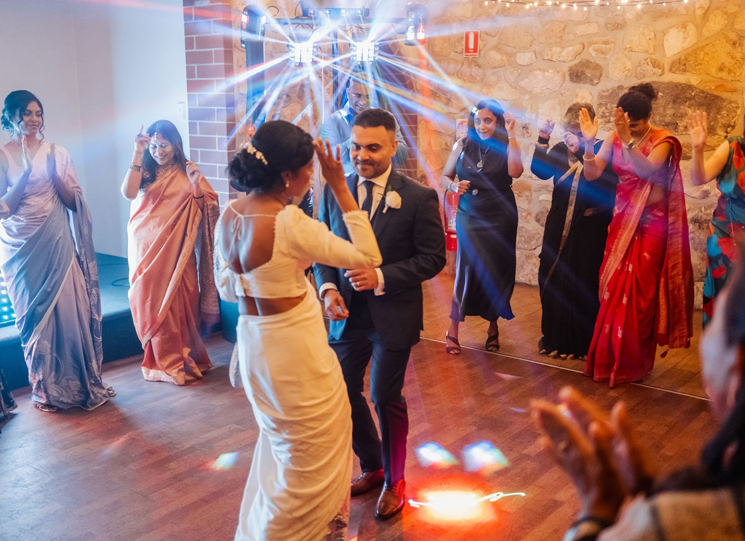 manor wedding in basket range - methmini & aravinda 175 Joyful couple dancing at a vibrant wedding reception with guests and colorful, festive atmosphere.