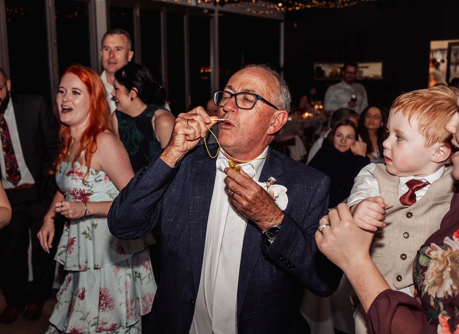 the lane vineyard wedding - caitlyn & craig 138 Elderly man whistles at joyous wedding celebration with playful child and festive guests.