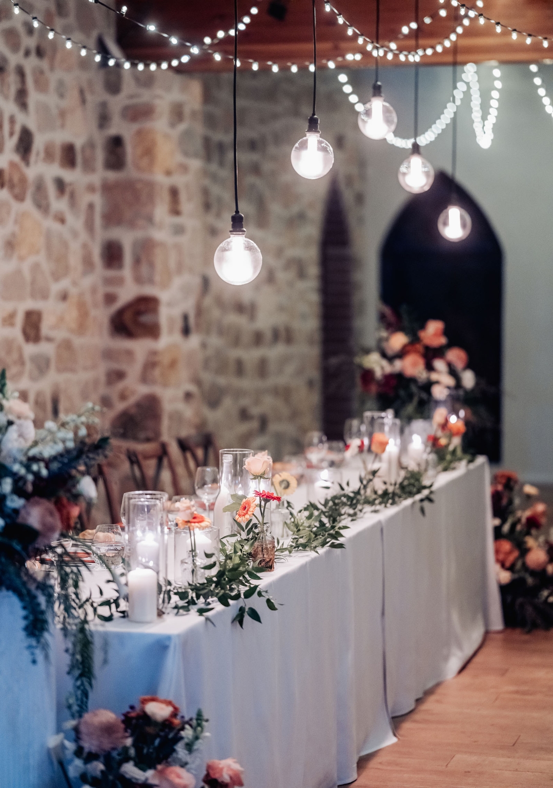 adelaide hills wedding at the manor - jo & dan 59 Rustic wedding reception table with candles, flowers, and glowing string lights.