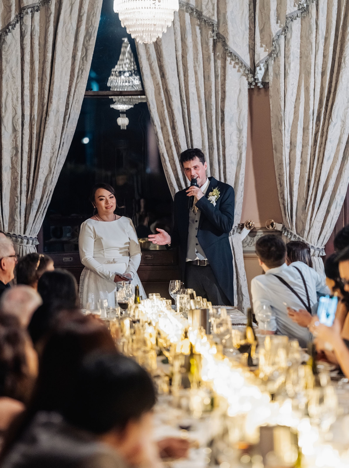 adelaide's st peter's cathedral wedding - irish & nick 59 Groom gives wedding reception toast beside bride in elegant candlelit dining room.