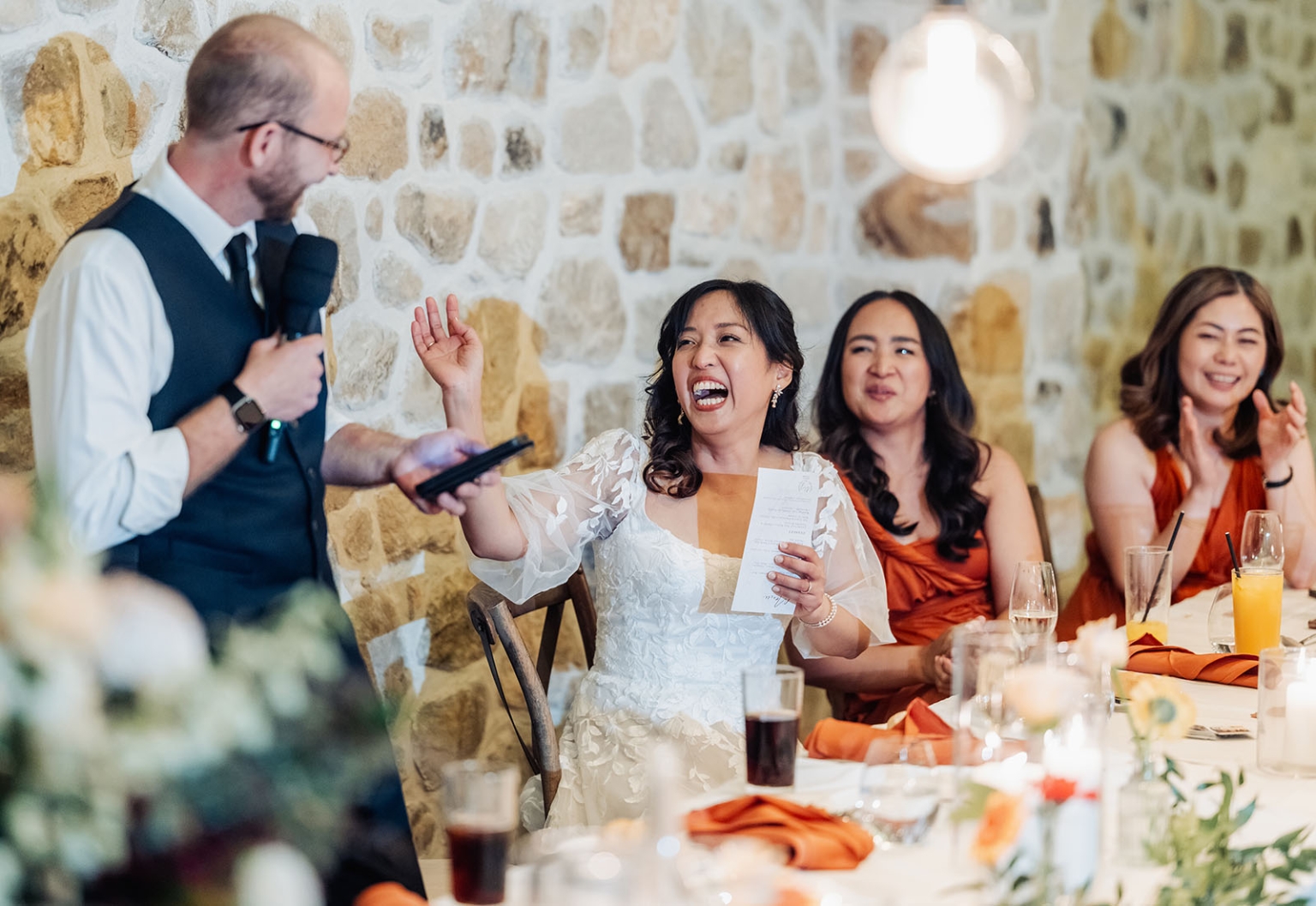 adelaide hills wedding at the manor - jo & dan 69 Bride laughing during rustic wedding reception toast with bridesmaids and host.