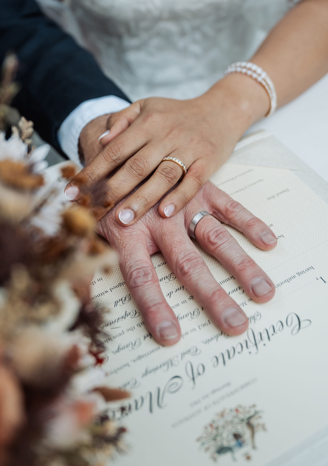 adelaide hills wedding at the manor - jo & dan 30 Wedding rings on hands over a signed marriage certificate.