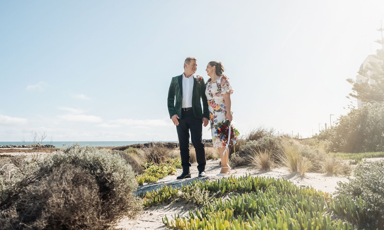 sa marriage office wedding – melissa & kyran 221 Beach wedding couple smiling on coastal path with bouquet and ocean view.