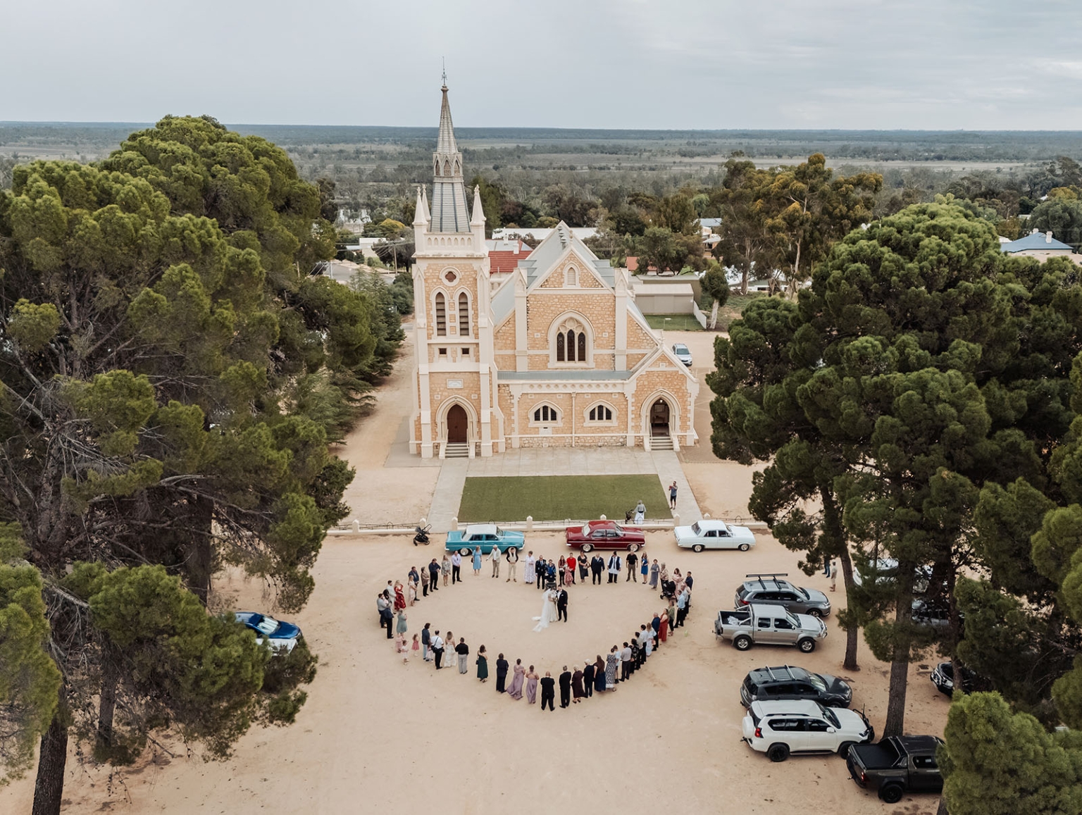 loxton's st peter's church wedding - madeline & brayden 42 Aerial wedding at historic rural church with bride, groom, and guests.