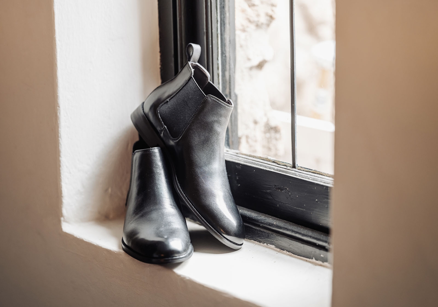 basket range wedding at the manor - leah & wes 19 Polished black leather Chelsea boots on a white windowsill.