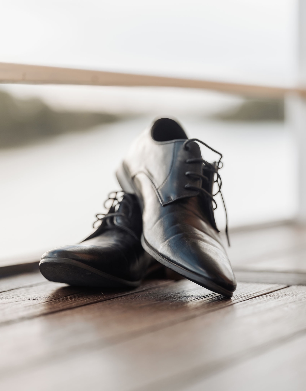 loxton's st peter's church wedding - madeline & brayden 1 Black leather dress shoes with loose laces on a wooden floor.