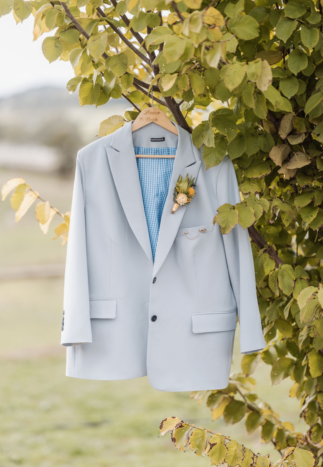 tiny house on the prairie wedding - lauren & bek 1 Pale blue bridal wedding suit jacket with boutonniere hanging on tree.