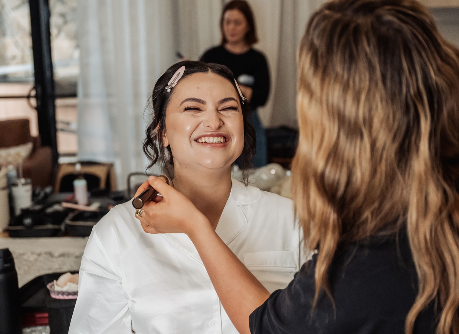 st george & st shenouda coptic church wedding - carmina & bill 17 Bride smiling during bridal makeup prep with artist in salon.