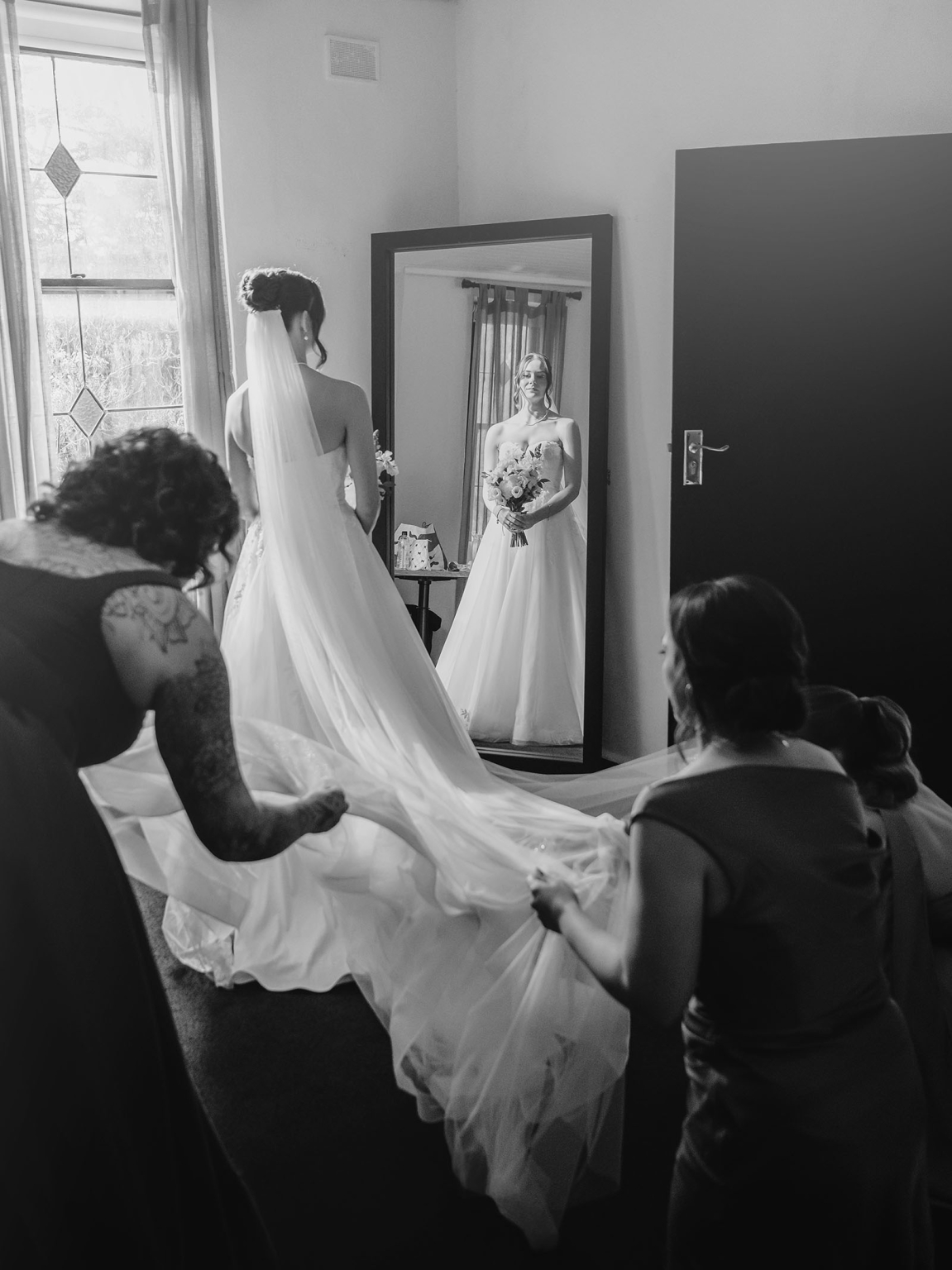 the manor wedding - crystal & mackenzie 23 Bride getting ready with veil and bouquet in mirror during wedding preparations.