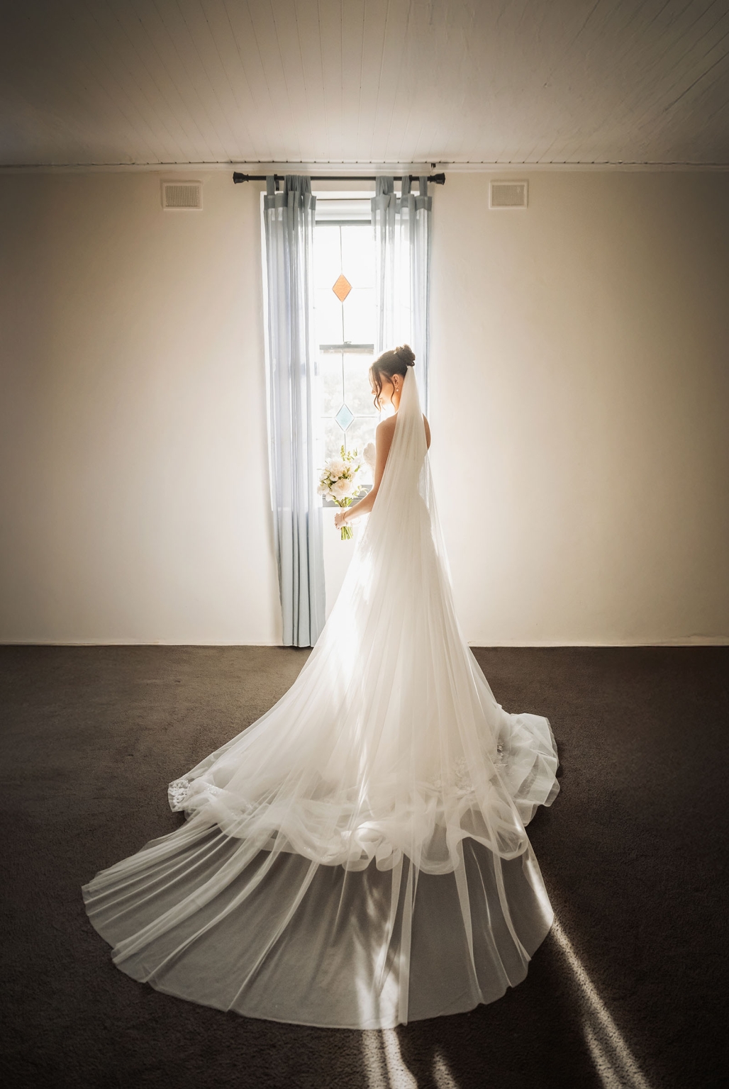 the manor wedding - crystal & mackenzie 25 Bride in elegant wedding gown and veil by sunlit window.