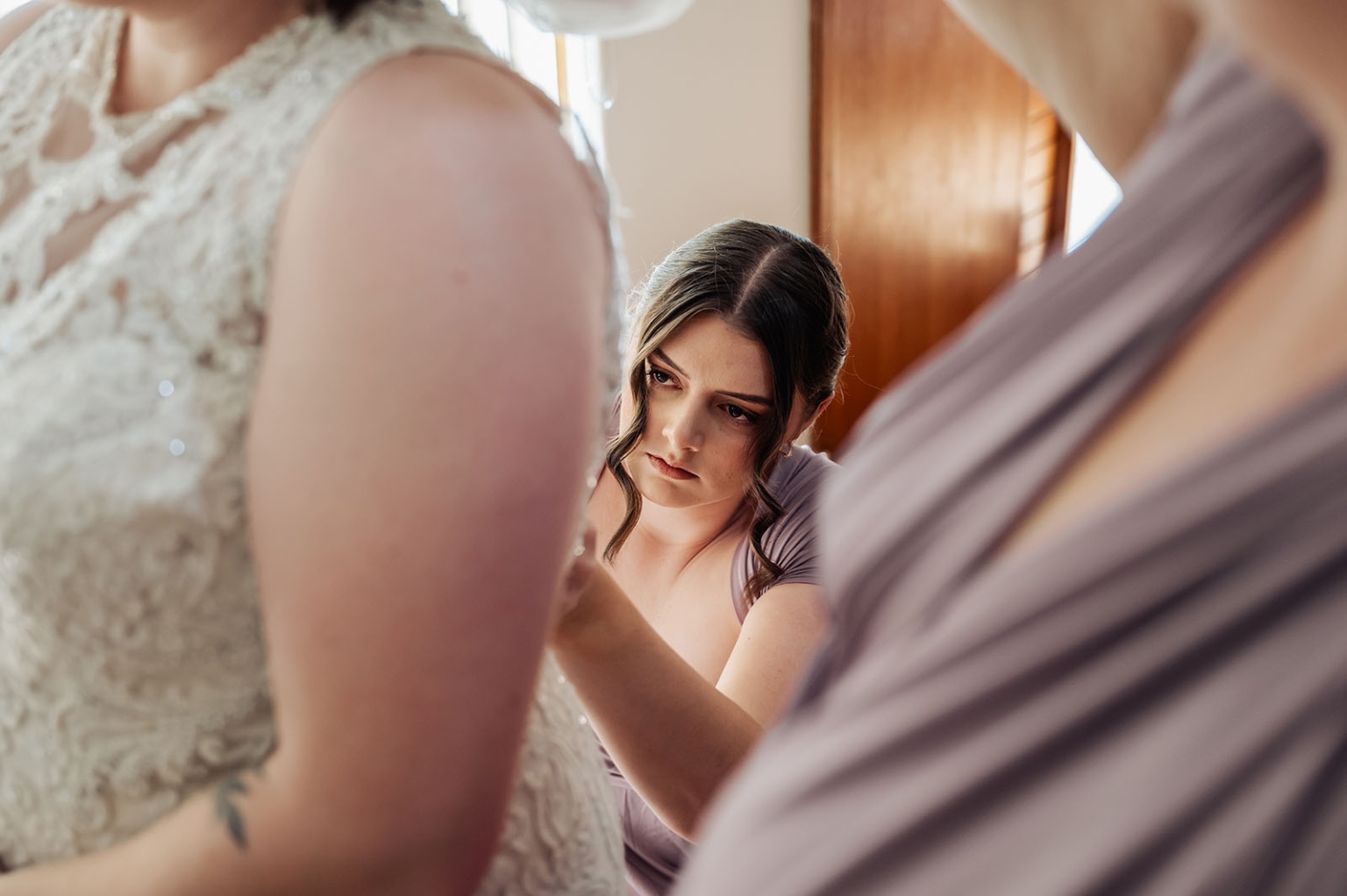 loxton's st peter's church wedding - madeline & brayden 24 Bridesmaid adjusting lace wedding dress during intimate bridal preparation.