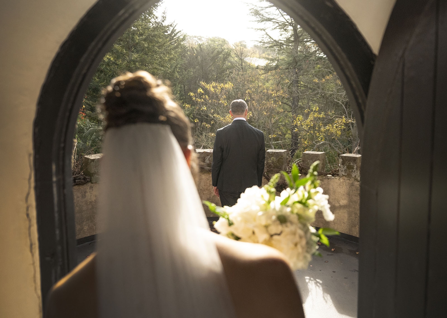 the manor wedding - crystal & mackenzie 30 Bride and groom first look through arched doorway at romantic wedding venue.