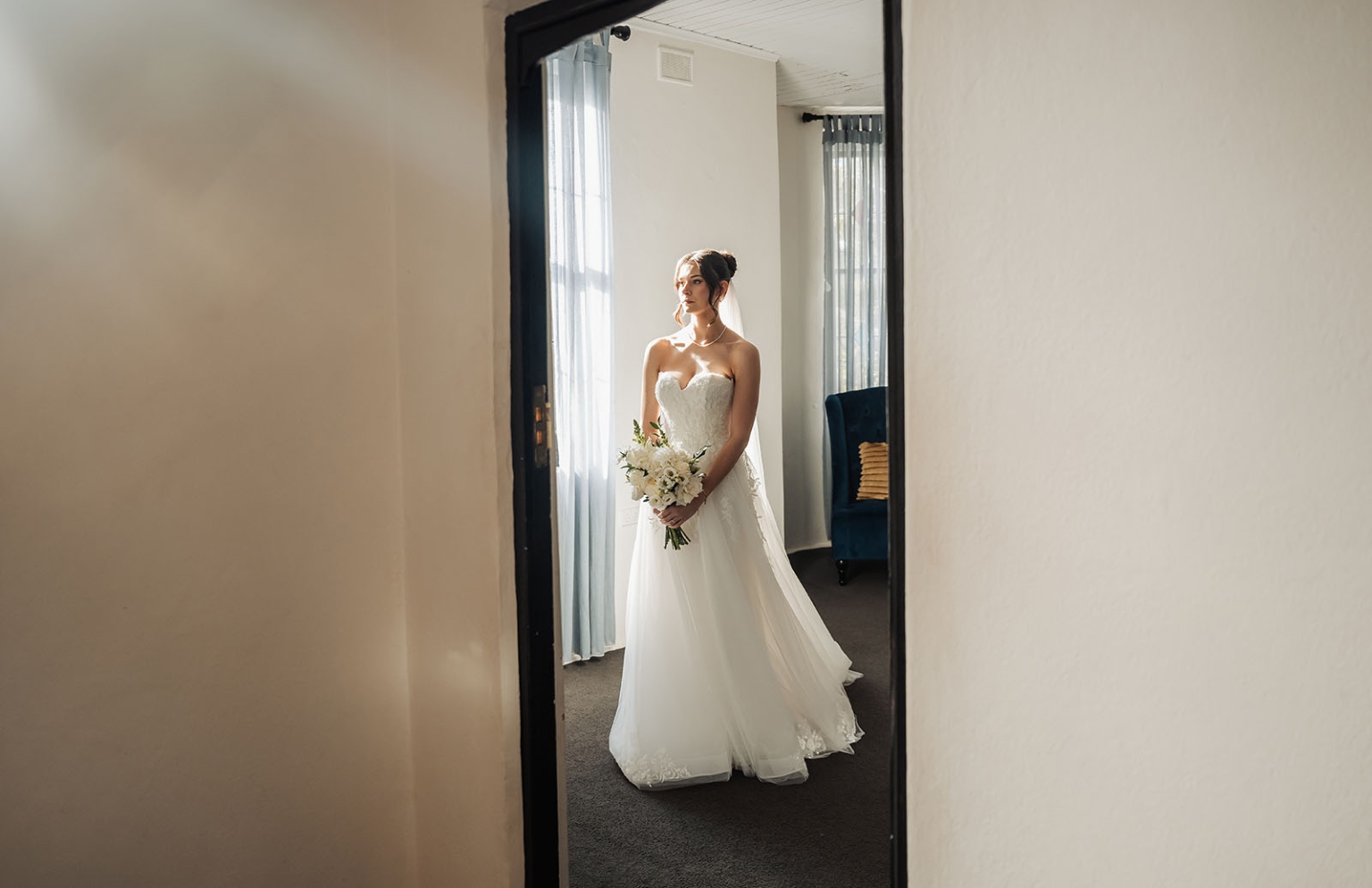the manor wedding - crystal & mackenzie 27 Bride in strapless wedding gown holding bouquet in soft window light.