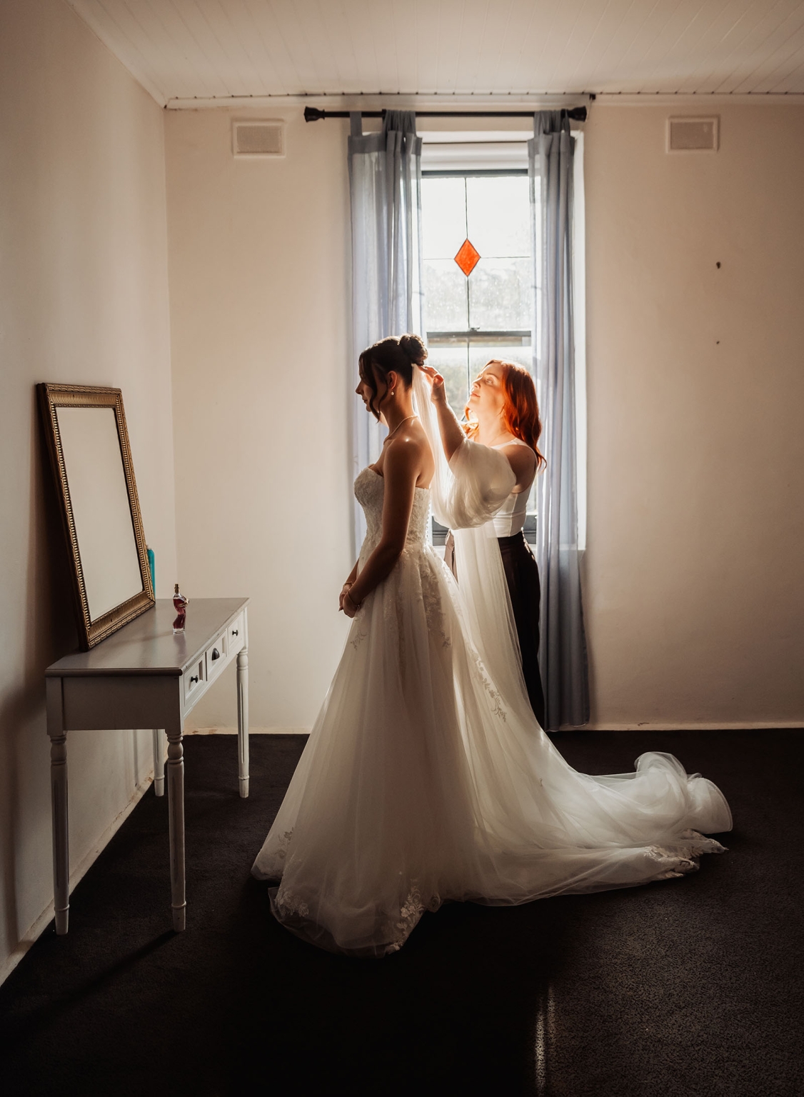 the manor wedding - crystal & mackenzie 20 Bride in white wedding gown getting veil adjusted in sunlit bridal suite.