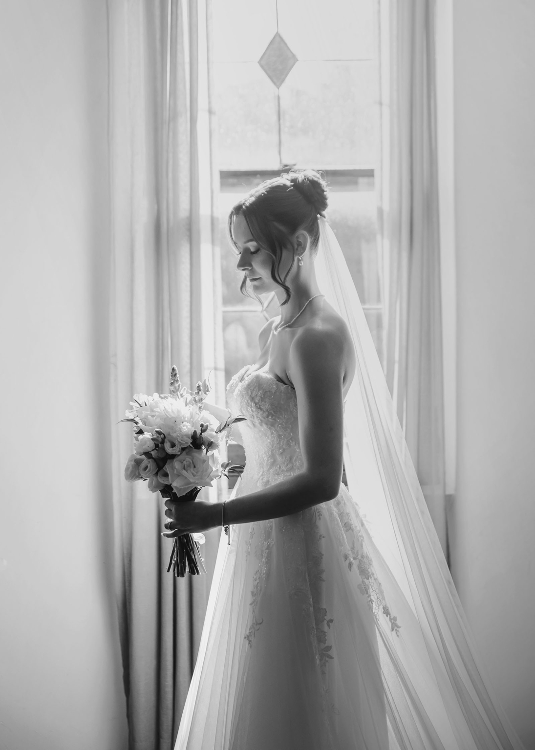 the manor wedding - crystal & mackenzie 22 Black-and-white bridal portrait by window with veil, bouquet, and wedding gown.