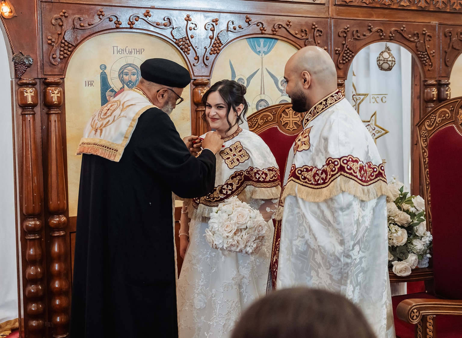 st george & st shenouda coptic church wedding - carmina & bill 41 Orthodox church wedding ceremony with bride, groom, and priest before ornate iconostasis.