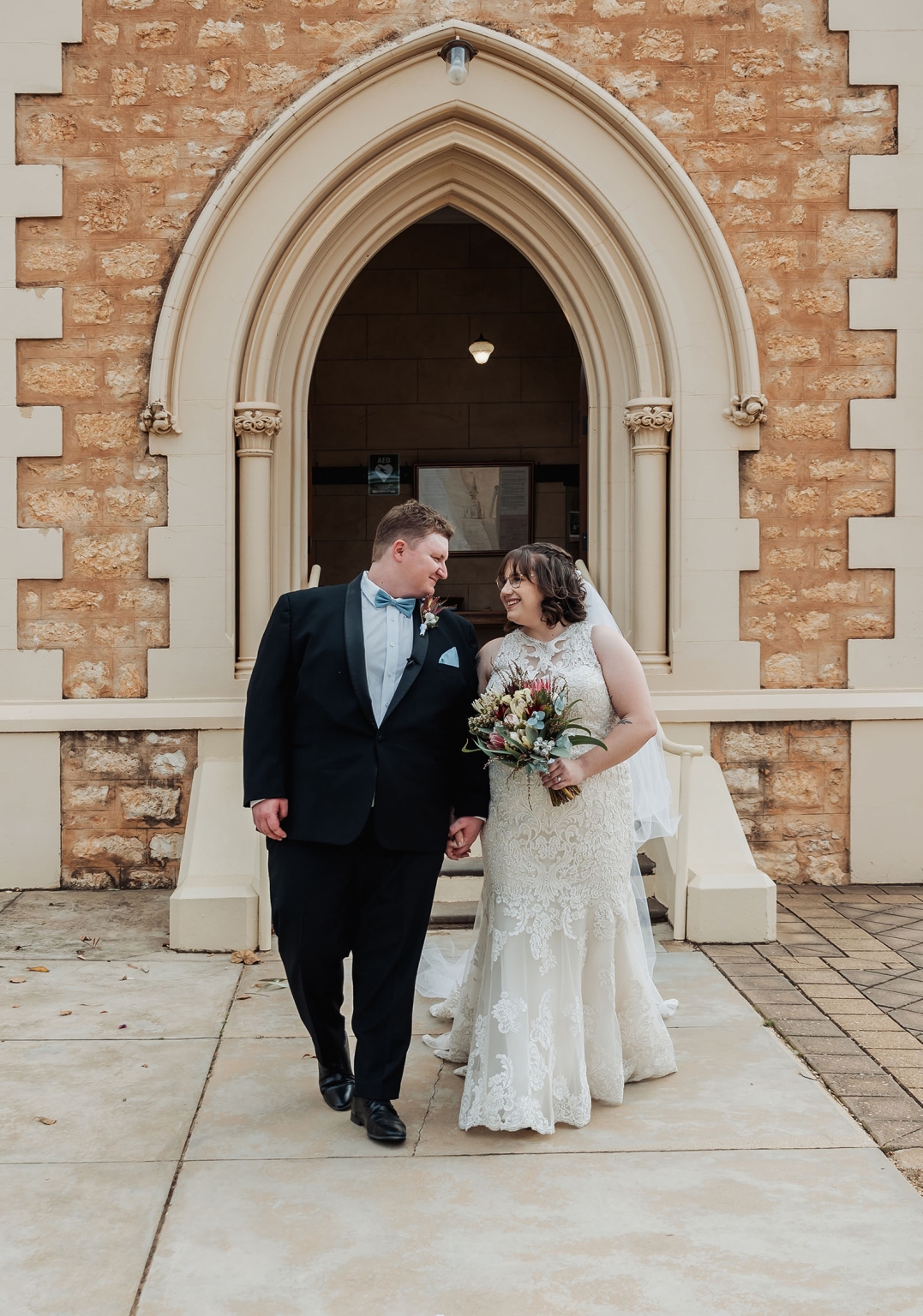 loxton's st peter's church wedding - madeline & brayden 40 Newlywed couple holding hands outside a historic church after their wedding ceremony.
