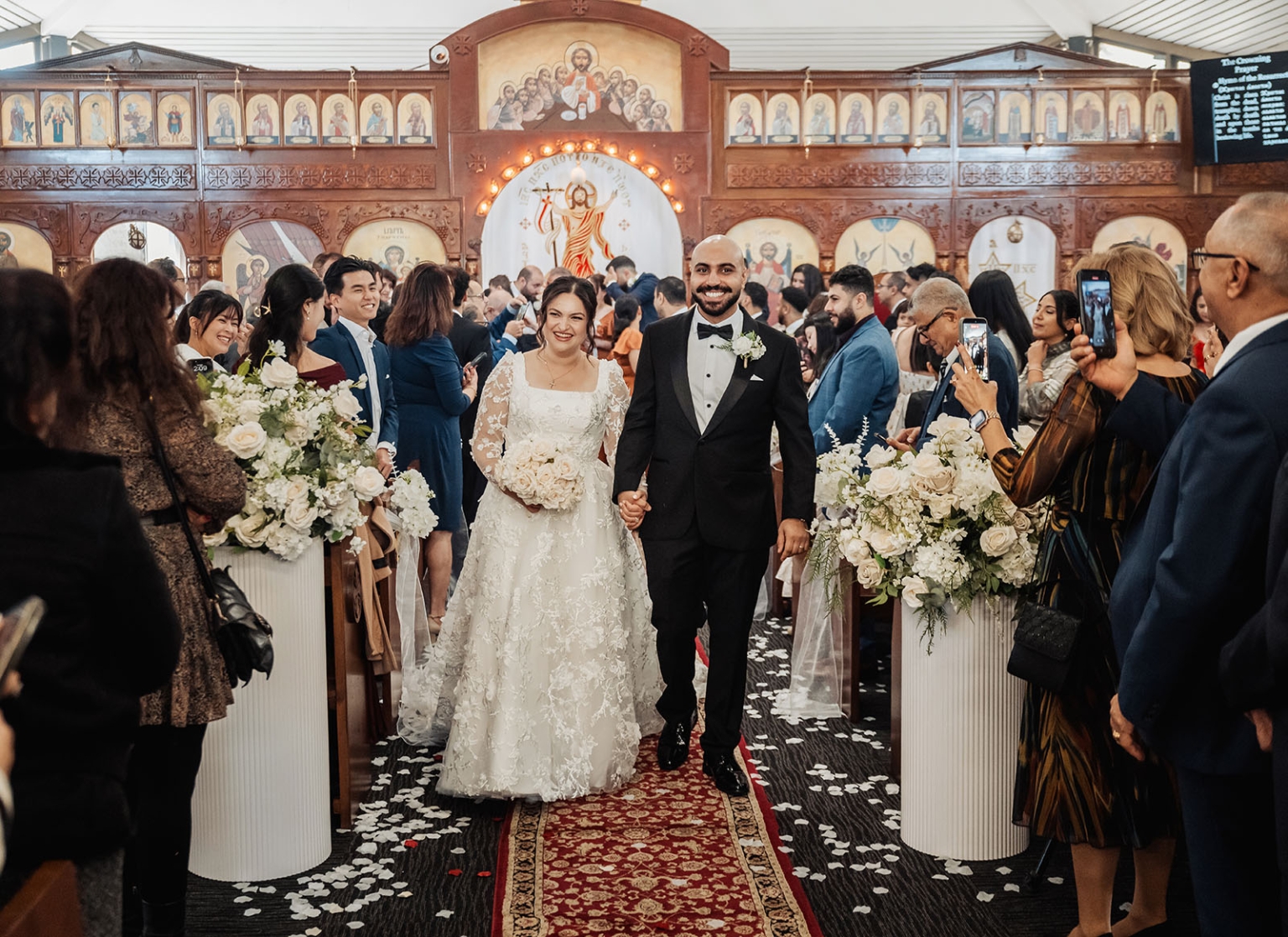 st george & st shenouda coptic church wedding - carmina & bill 52 Bride and groom in Orthodox church wedding procession with elegant floral aisle decor.