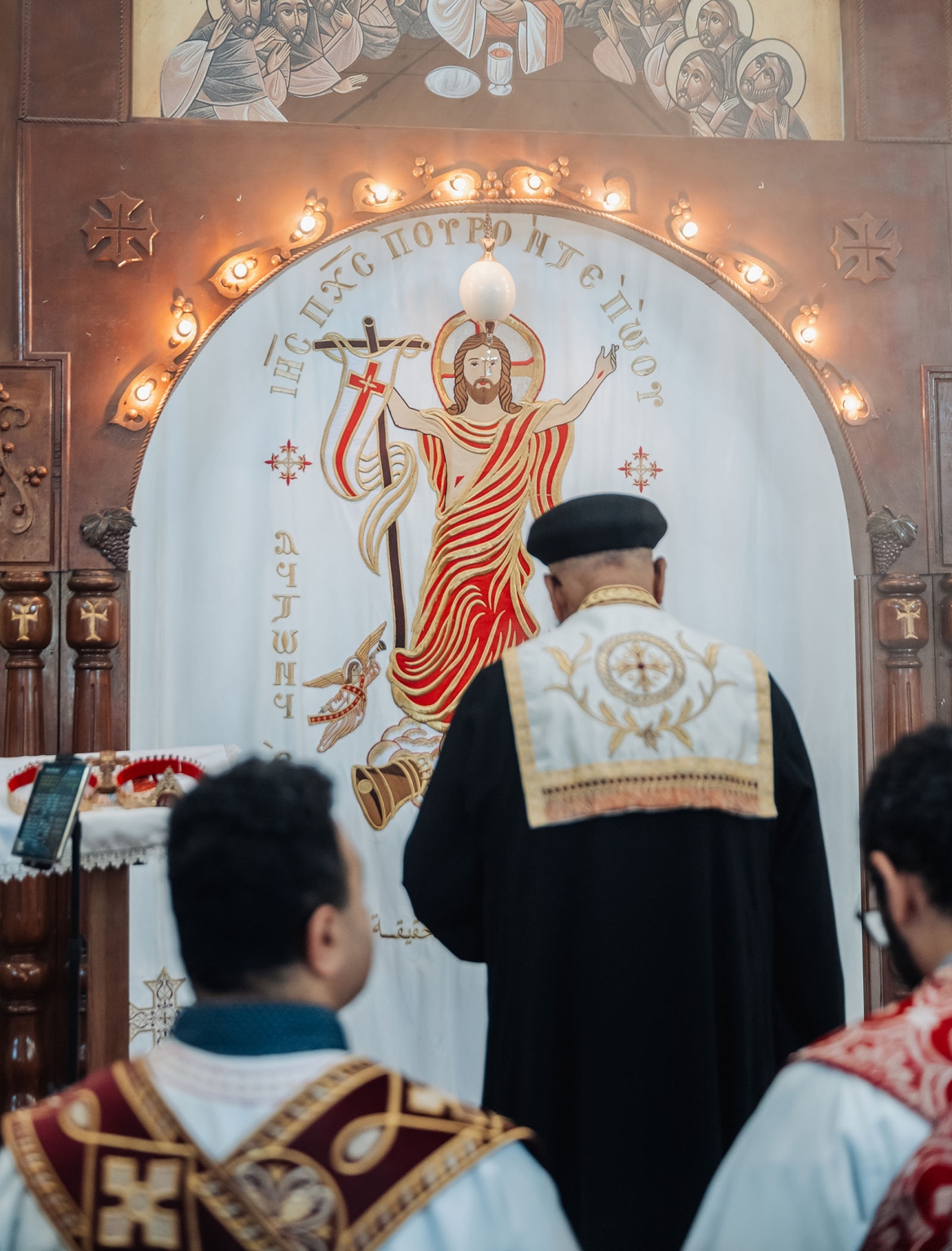 st george & st shenouda coptic church wedding - carmina & bill 43 Coptic Orthodox liturgy curtain with risen Christ icon, altar, and clergy.