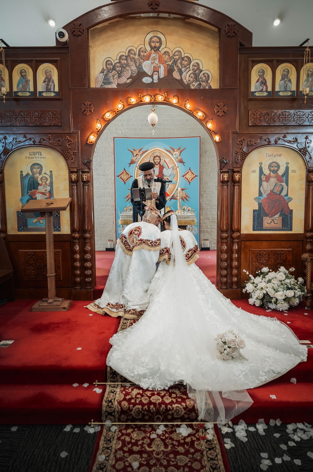 st george & st shenouda coptic church wedding - carmina & bill 49 Coptic Orthodox wedding ceremony with bride and groom kneeling before priest.