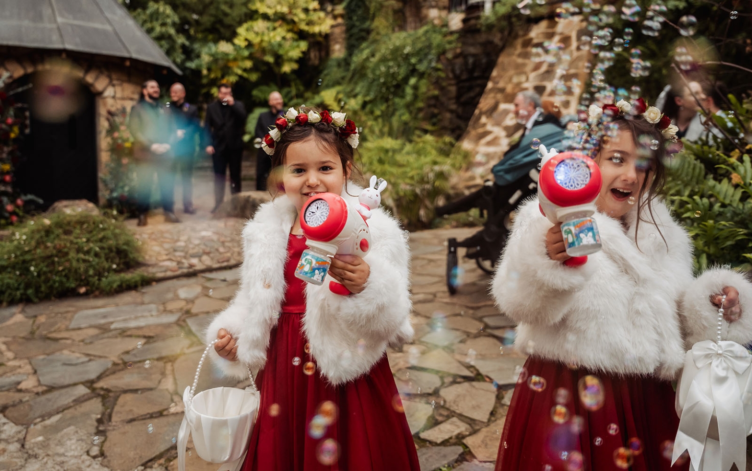 basket range wedding at the manor - leah & wes 45 Flower girls blowing bubbles in red dresses at outdoor garden wedding.