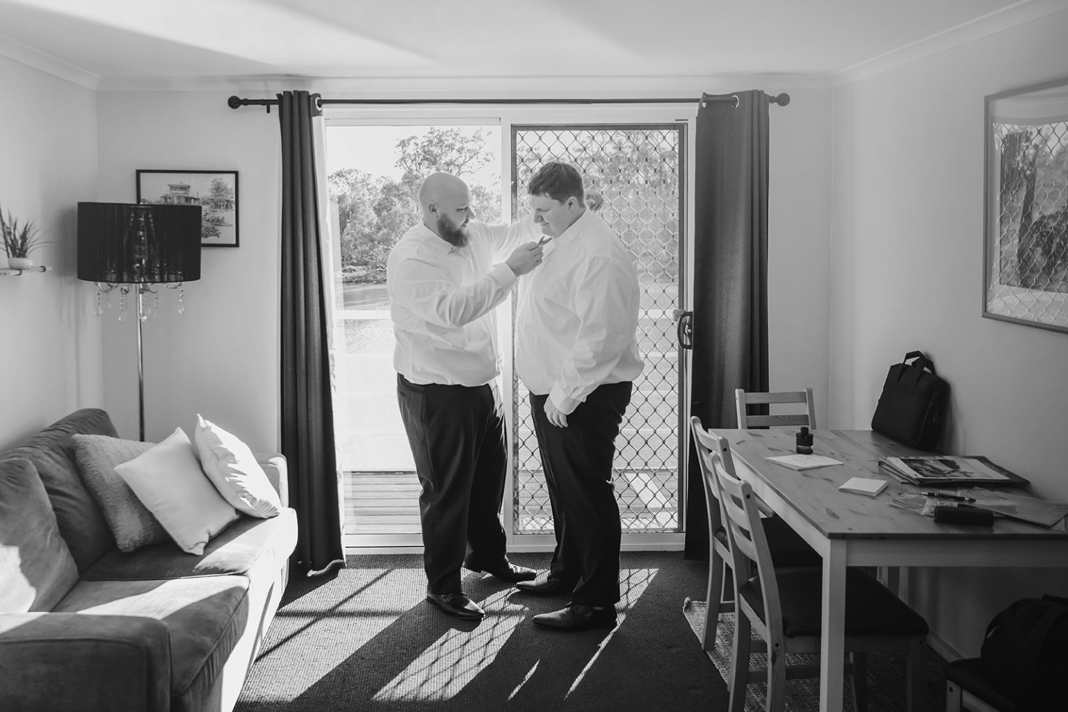 loxton's st peter's church wedding - madeline & brayden 4 Best man adjusts groom’s collar in sunlit room before wedding.