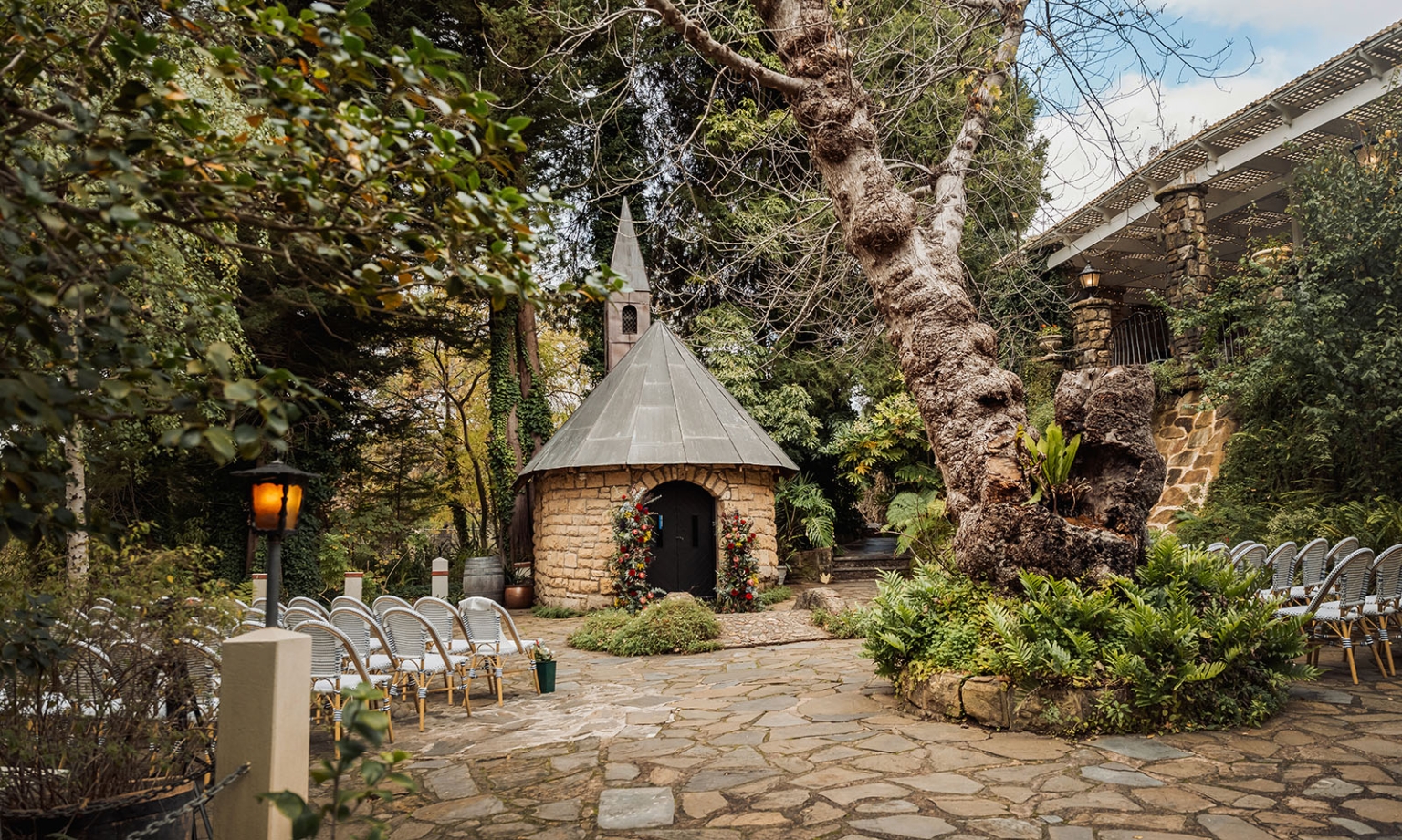basket range wedding at the manor - leah & wes 41 Rustic garden wedding chapel with stone courtyard, floral entrance, and ceremony chairs.
