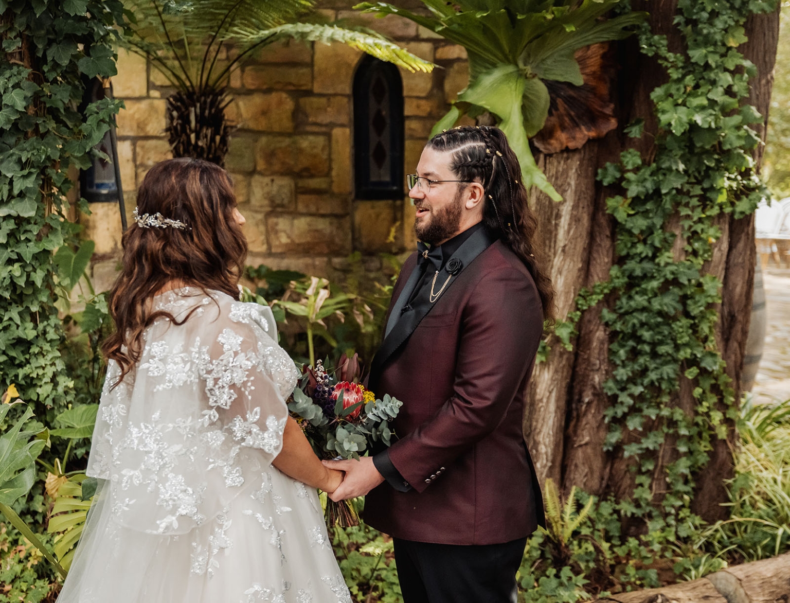 basket range wedding at the manor - leah & wes 29 Garden wedding couple holding bouquet, bride in lace gown and groom in burgundy suit.